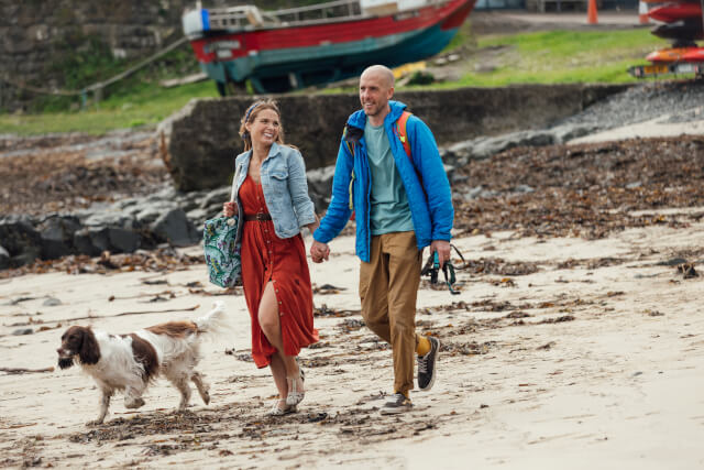 Couple walking their dog on a beach in Northumberland