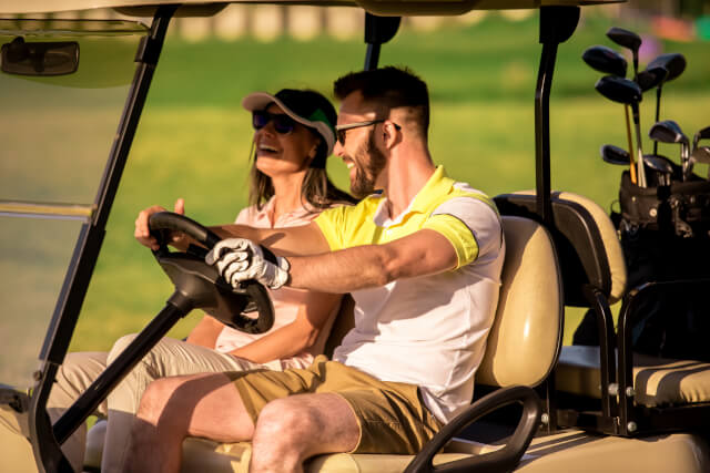 couple driving golf caddy