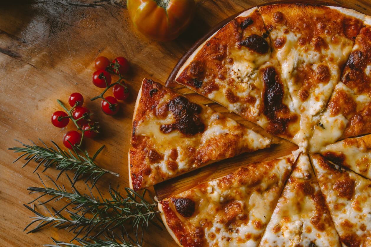 magherita pizza with a garnish of tomatos and rosemary