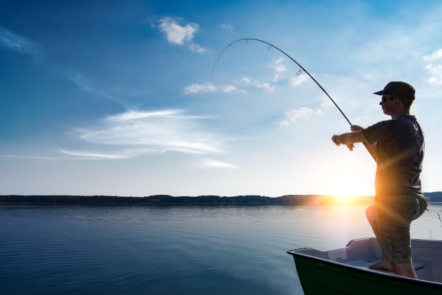 man angling in large body of water